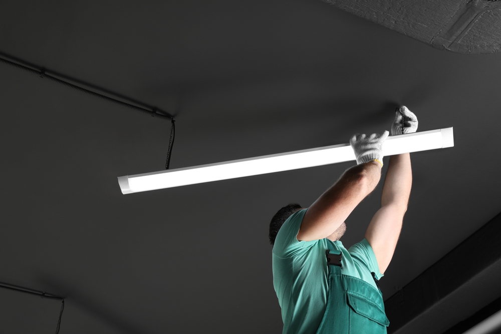 ผู้ชายกำลังทำตามขั้นตอนการเปลี่ยนหลอดไฟ LED ภายในบ้าน